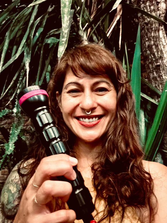 Arielle @arielleunderwater holding the LED ONE MINI backup light from AMMONITE SYSTEM in a jungle.